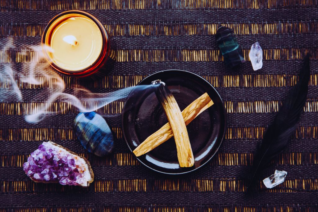 wooden table with candle together with palo santo and gemstones on top x no credit needed